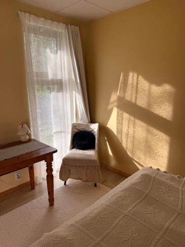 a bedroom with a bed and a chair and a window at Eha Farmstay in Rõuge