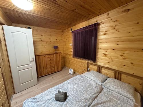 a bedroom with a bed in a wooden cabin at Faház - Nyaraló a Tiszánál in Tiszacsege