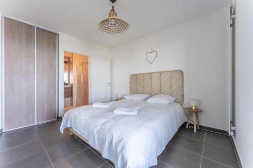 une chambre avec un grand lit blanc avec deux oreillers dans l'établissement immeuble haut standing avec vue étang et parking, à Mauguio