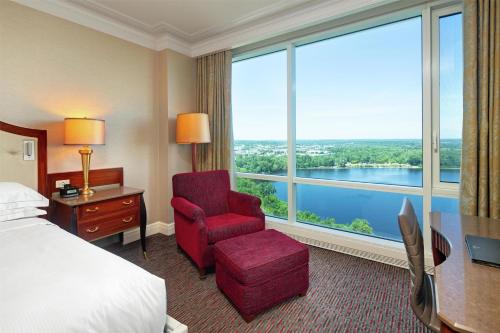 a hotel room with a bed and a chair and a large window at Hilton Lac-Leamy in Gatineau