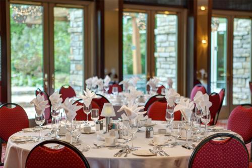 a dining room with tables and red chairs and glasses at Hilton Lac-Leamy in Gatineau