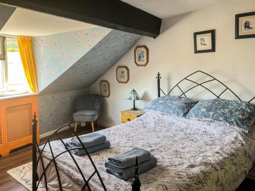 a bedroom with a bed and a chair and a window at Willow Cottage in Spark Bridge