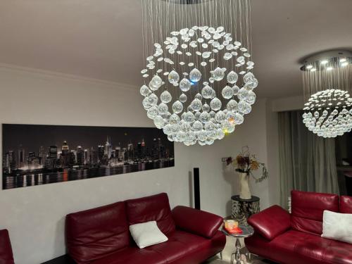 a living room with a red couch and a chandelier at Splendide appartement style new-yorkais de 180 m2 à mobilart vue mer pour famille uniquement in Oran