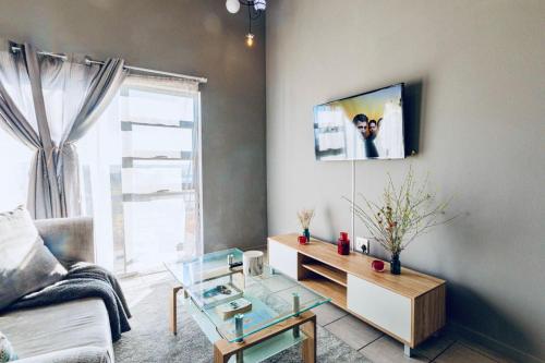 Una sala de estar con un sofá y una mesa de cristal. en Dainfern Fourways apartment offering privacy and a lavishly expansive balcony views, en Sandton