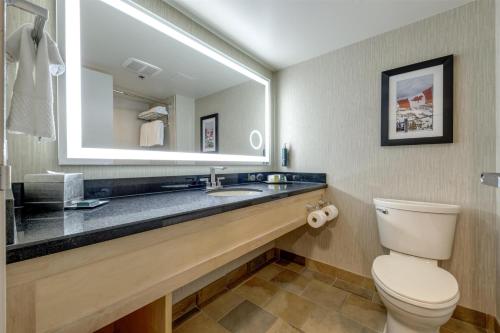 a bathroom with a sink and a toilet and a mirror at Hilton Whistler Resort & Spa in Whistler