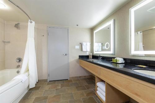 a bathroom with a sink and a tub and a mirror at Hilton Whistler Resort & Spa in Whistler