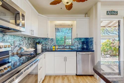 a kitchen with white cabinets and blue tiles at Puamana 30-2 in Lahaina
