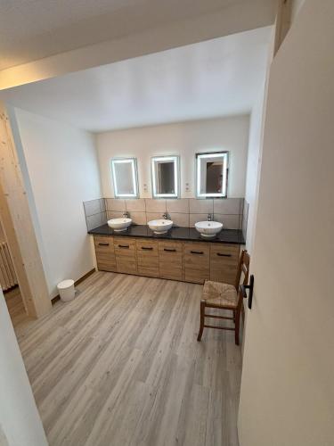 une salle de bain avec trois lavabos et une chaise dans l'établissement Le Villard appartement Adrech, à Abriès