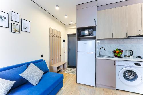 a living room with a blue couch and a kitchen at 1 room apartment CITY PLUS 2 in Almaty