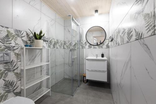 a bathroom with a shower and a sink and a mirror at Domki Leśny Zakątek in Pogorzelica