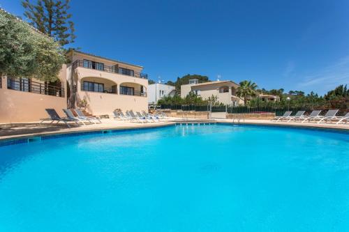 a large blue pool with chairs and a house at Mar Hotels Alcanada in Port d'Alcudia