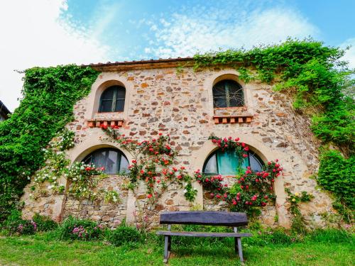 a building with flowers and a bench in front of it at Tuscan Farmhouse in the Countryside in Serravalle Pistoiese