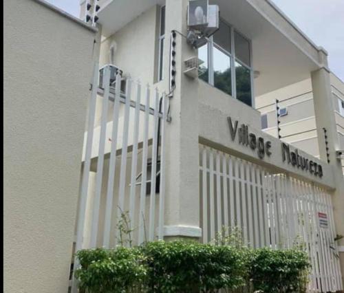 a building with a white fence in front of it at Apartamento Moderno & Mobiliado - Próximo ao Aeroporto, Condomínio Village Natureza in Juazeiro do Norte