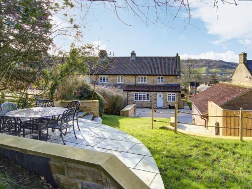 a patio with a table and chairs in a yard at West House in Cowesby