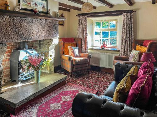 ein Wohnzimmer mit Kamin und einer Couch und Stühlen in der Unterkunft Mill Close Cottage in Chesterfield