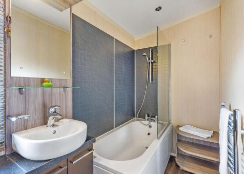 a bathroom with a tub and a sink and a bath tub at Cheddar Woods Resort And Spa in Cheddar
