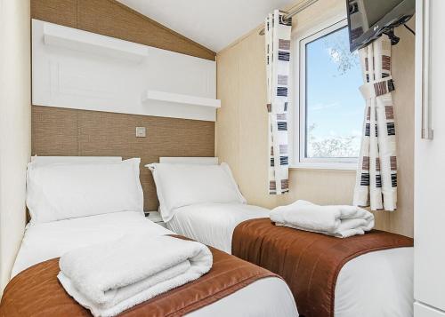 two beds in a room with a window at Cheddar Woods Resort And Spa in Cheddar