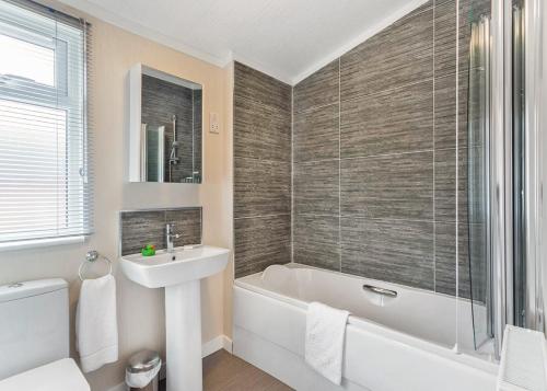 a bathroom with a sink and a tub and a toilet at Cheddar Woods Resort And Spa in Cheddar