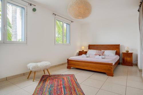 a bedroom with a bed and two windows and a rug at Villa Célestine in Saint-Paul