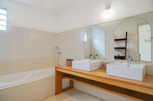 a bathroom with two sinks and a tub and a mirror at Villa Célestine in Saint-Paul