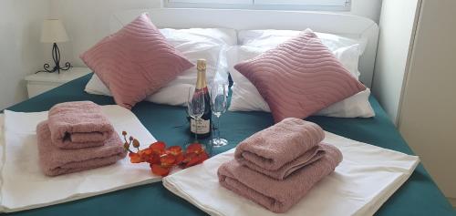 ein Bett mit Handtüchern und einer Flasche Wein darauf in der Unterkunft Apartmani Sara Marija in Karlobag