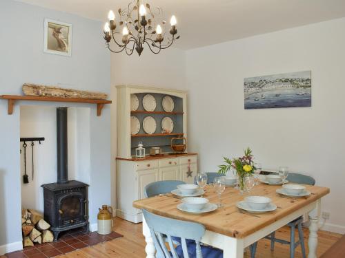 ein Esszimmer mit einem Holztisch und einem Herd in der Unterkunft Elm Cottage in Whitwell