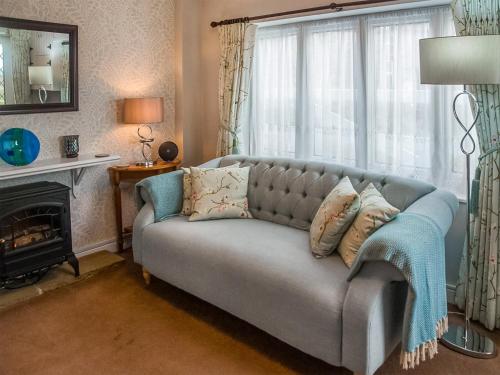 a couch in a living room with a window at Apple Blossom Cottage - Uk46648 in Cheddar