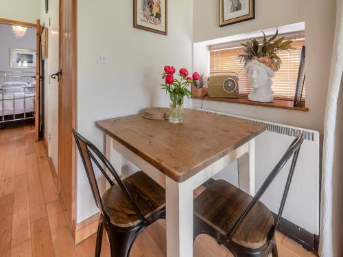 a dining room table with two chairs and a vase of flowers at Lidsey Farmhouse in Bognor Regis