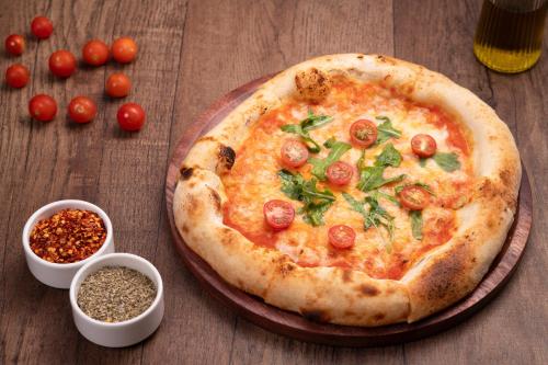 a pizza on a table with tomatoes and spices at Holiday Inn Gurgaon NH8 by IHG in Gurgaon