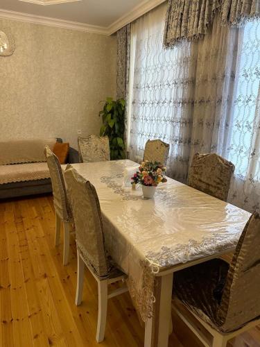 a dining room table with chairs and a table with flowers on it at Mountain's Villa in Gabala