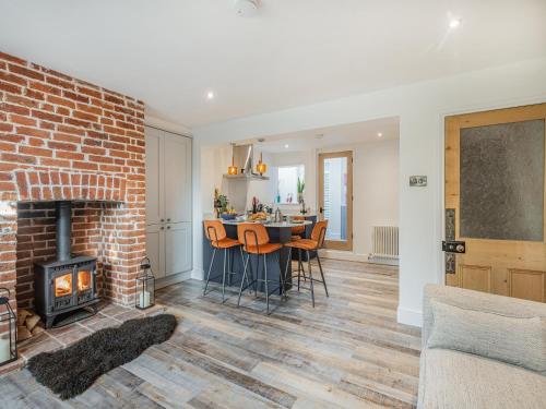 een woonkamer met een open haard en een tafel met stoelen bij Lavender Cottage in Coltishall