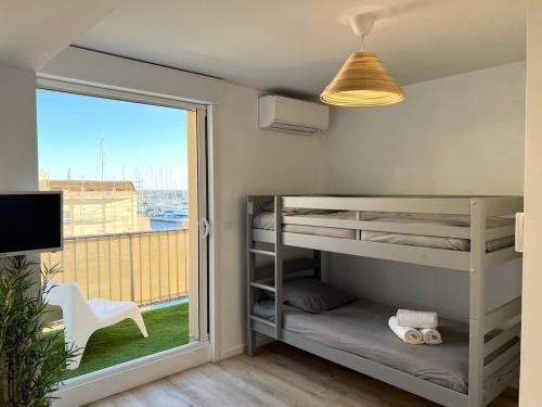 Cette petite chambre comprend des lits superposés et une fenêtre. dans l'établissement Bel appartement avec piscine et vue bateaux, à Gruissan