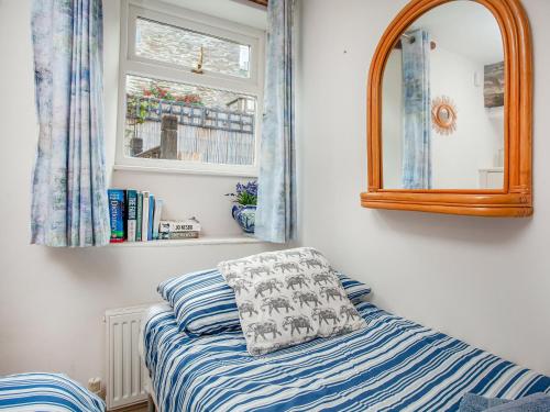 a bedroom with a bed and a mirror and a window at Gypsett in Polruan