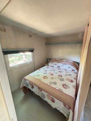 - un petit lit dans une petite chambre avec fenêtre dans l'établissement Mobil Home dans propriété privée, à Béziers