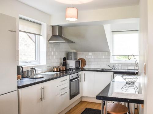 a kitchen with white cabinets and a black counter top at Sheep's View Cottage in Eastbourne