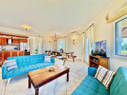ein Wohnzimmer mit blauen Sofas und einem Tisch in der Unterkunft Beachfront Villa JustRelax with private pool by DadoVillas in Acharavi