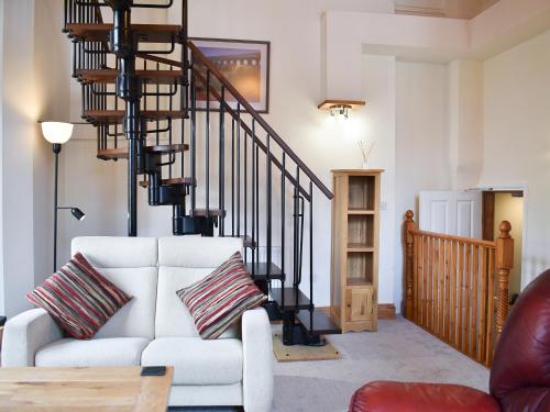 a living room with a white couch and a spiral staircase at Inglewood Terrace in Penrith