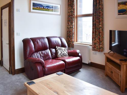 a living room with a brown leather couch and a tv at Inglewood Terrace in Penrith