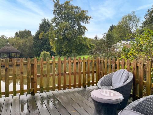 a wooden deck with two chairs and a fence at Lake View Cottage in Belper