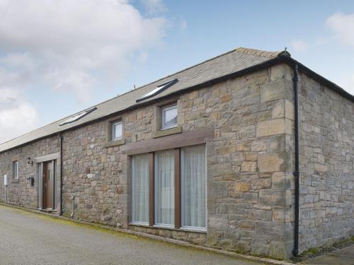 a stone building with windows on a street at Stable Cottage in Chatton