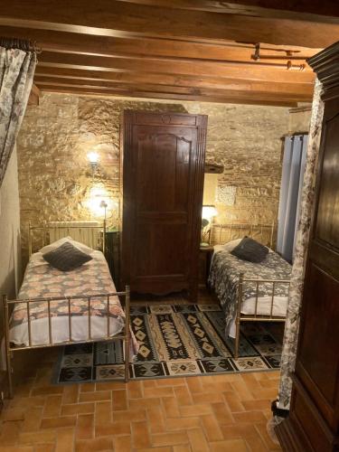 - une chambre avec 2 lits dans une pièce en pierre dans l'établissement Maison Périgourdine de charme dans la campagne proche de Bergerac, à Saint-Nexans