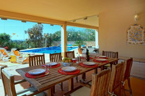 a wooden table with chairs and a dining room with a pool at Casa Alha in Carvoeiro