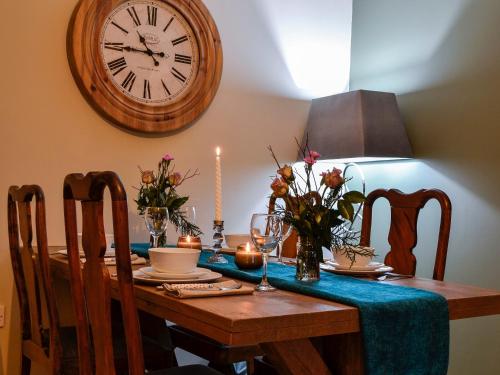 a dining room table with a clock on the wall at Cotlea East Cottage in Alyth