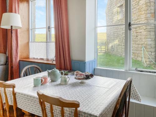 a dining room table with a white table cloth and a window at Gable End Cottage in Goathland