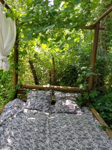 un jardin avec une pergola en bois et un banc dans l'établissement Insolite - Nuit à la belle étoile dans gazébo thaï près de la rivière, à Les Plantiers