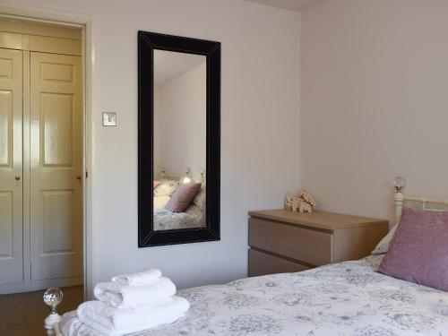 a bedroom with a bed with a mirror and a dresser at Barn House in Settle