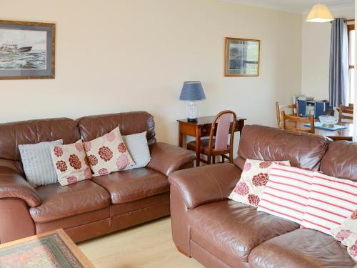 a living room with a brown leather couch at Lochinchard Cottages in Kinlochbervie