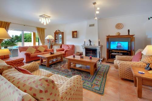 a living room with couches and a tv at Casa Alha in Carvoeiro