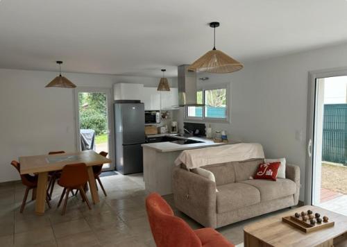 un salon et une cuisine avec un canapé et une table dans l'établissement Maison Cosy T4 proche de la mer, à Saint-Brévin-lʼOcéan