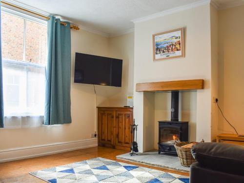 a living room with a fireplace and a flat screen tv at Pilchard Cottage in Scarborough